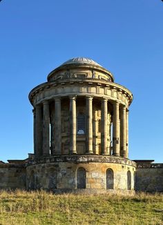 an old stone building sitting on top of a lush green field under a blue sky