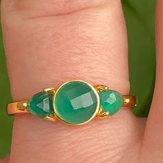 a close up of a person's hand wearing a ring with two green stones