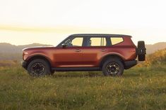 an orange suv parked on top of a lush green field