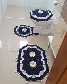 two crocheted rugs sitting on the floor next to a toilet in a bathroom