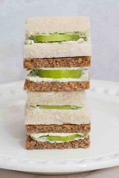 three sandwiches stacked on top of each other with cucumber slices in between them