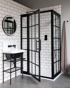 a black and white tiled bathroom with a shower stall, sink and mirror on the wall