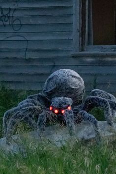 a giant spider statue with glowing eyes in front of a house