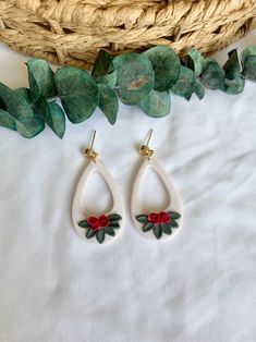 the earrings are decorated with red flowers and green leaves, along with a wicker basket