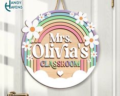 a wooden sign that says mrs olivaa's classroom hangs on the front door