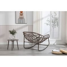 a living room with white walls and wooden flooring, including a wicker rocking chair