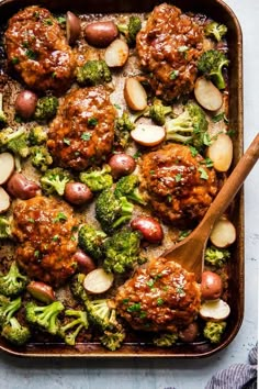 meatballs and broccoli in a pan with a wooden spoon