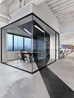 an empty office with glass walls and tables in the center, looking out onto the city