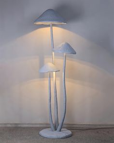 three white lamps sitting next to each other on top of a cement floor in front of a wall