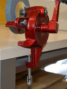 a red piece of metal being worked on with a circular sawtoothing machine in the background