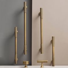 an assortment of brass fixtures on display against a gray wall, including two handles and one door handle