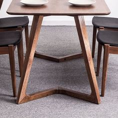 a wooden table with four chairs around it and plates on top of the table in front of them