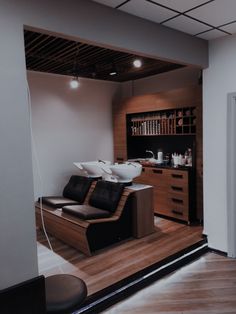 a salon with black leather chairs and wooden flooring in front of a book shelf