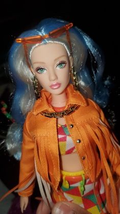 a doll with blue hair wearing an orange jacket