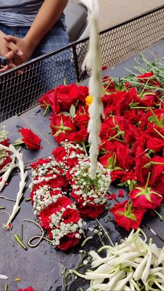 red and white flowers are laid out on the ground next to a wire fence with a person in the background