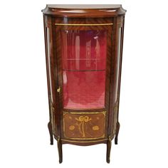 an antique cabinet with red glass doors and gold trimmings on the bottom shelf