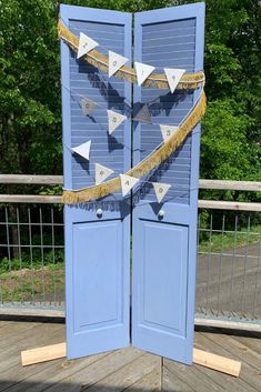 an open blue door with yellow and white decorations on the outside, in front of some trees