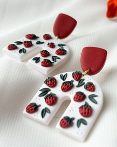 two white and red earrings with strawberries on them