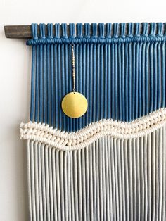 a blue and white wall hanging with a gold disc on it's side,