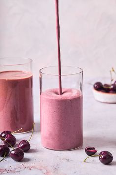 two glasses filled with smoothie next to cherries