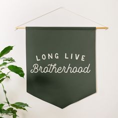 a green banner hanging on a wall with the words long live brotherhood written in white