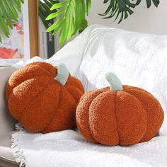 two orange pumpkins sitting on top of a white couch