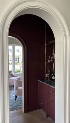 an archway leading into a living room with red walls and furniture in the doorways