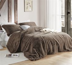 a bedroom with a large bed covered in brown comforter and pillows on the floor