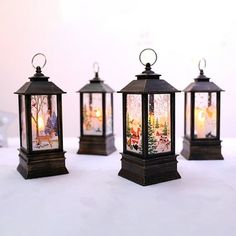 three lanterns with christmas scenes on them are sitting next to each other in front of a white background