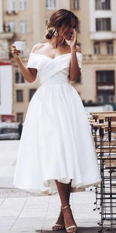 a woman in a white dress holding a coffee cup