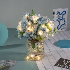 a vase filled with white and blue flowers on top of a table next to balloons