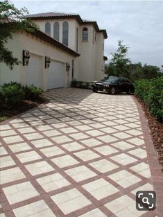 a car is parked in front of a house with two garages and a driveway