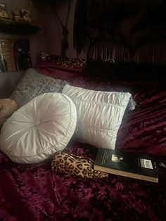 there is a stuffed animal on the bed with pillows and a book next to it