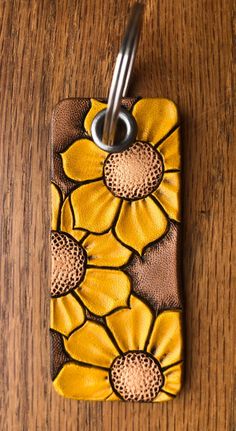 a yellow and brown flower cell phone case on a wooden table with a metal hook