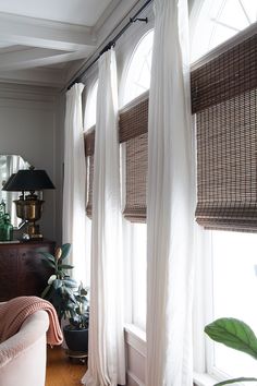 a living room filled with furniture and windows covered in white curtained drapes