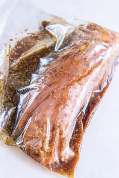 a piece of meat wrapped in plastic sitting on top of a white tablecloth covered counter