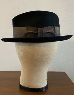 "For your consideration Vintage 60s era CHAMP KASMIR Finish black fedora hat Gold wide grosgrain ribbon 2\" wide Leather sweatband Shows some light dust from storage & minor wear .. couple minor indentions (top crown and large one on side crown) .. interior liner shows age with light dust and soiling , nicely broken in and very handsome! 100% Fur felt Manufacturing tag on inside sweatband Tag marked size 7 1/8 or 57 cm or Medium Shown on vintage size medium mannequin 2.\" brim 4\" crown 6 2/ Custom Fitted Top Hat For Kentucky Derby, Retro Fitted Fedora With Curved Brim, Retro Fedora With Curved Brim, Retro Fitted Brimmed Felt Hat, Fitted Retro Fedora With Curved Brim, Black Hat Bands For Kentucky Derby With Curved Brim, Custom Fitted Hat With High Crown, Fitted Black Top Hat With High Crown, Retro Fitted Fedora With Brim