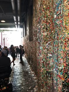 many people are walking through an alley way covered in confetti and plastic bottle caps