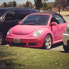 two cars parked next to each other in a parking lot with grass on the ground