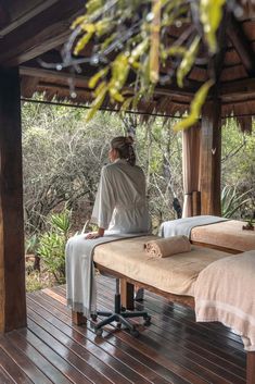 a woman sitting on top of a wooden bench next to another person in a bathrobe