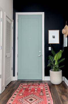 a blue door in a black and white room with a red rug on the floor