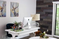 a white desk topped with a laptop computer next to a plant filled vase on top of a table