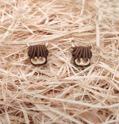 two small wooden earrings on top of dry grass