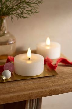 three lit candles sitting on top of a wooden table