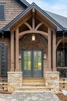 the front entrance to a home with stone steps and pillars, arched glass doors and brick paversed walkway