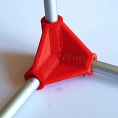 an orange plastic object sitting on top of a white table next to a metal pole