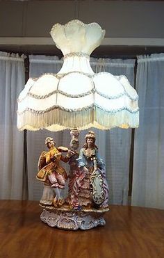 a lamp that is sitting on top of a wooden table in front of some curtains