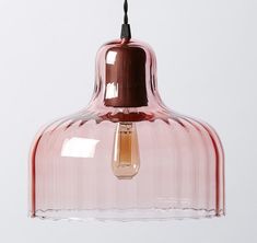 a pink glass pendant light hanging from a ceiling fixture with a black cord attached to it