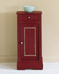 a red cabinet with a bowl on top