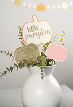 a white vase filled with flowers and cut out pumpkins sitting on top of a table